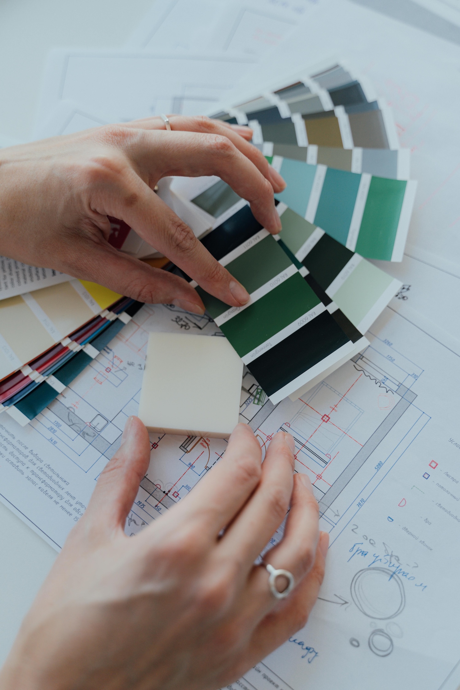 Photo of hands going through color swatches on top of interior design plans.